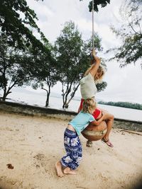 Girl embracing woman sitting on rope swing 