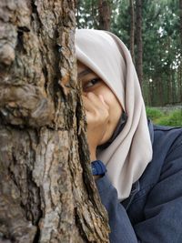 Portrait of woman with tree trunk