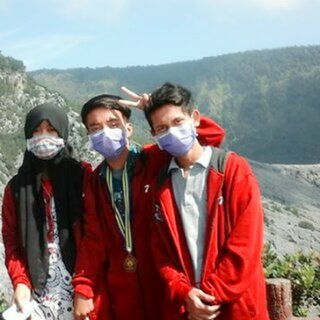 FRIENDS STANDING ON FIELD AGAINST MOUNTAIN