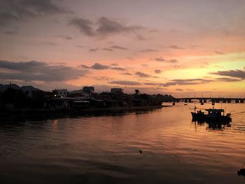 Silhouette boats in sea against orange sky