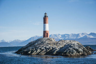 Lighthouse by sea against sky