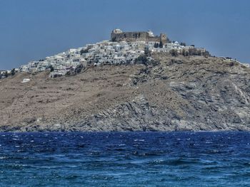 Building by sea against clear blue sky