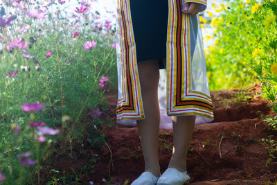 Low section of woman standing on flowering plants