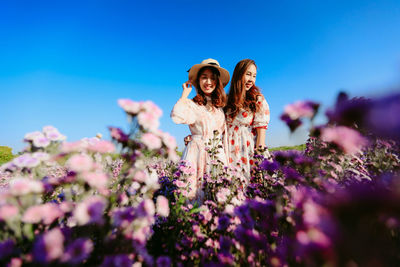 Full length of woman standing by flowering plants against sky