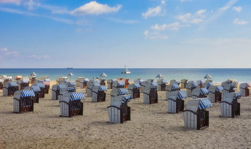 Hooded chairs on beach against sky