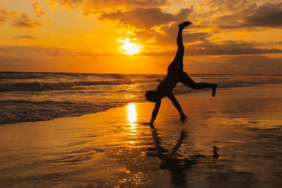 Silhouette woman jumping at sunset