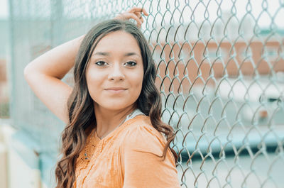 Portrait of a smiling young woman in chainlink fence