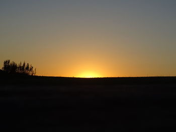 Silhouette landscape against clear sky during sunset