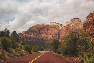 Road amidst rocks and trees against sky