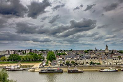 Bridge over river by buildings in city against sky