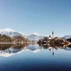 Scenic view of lake by mountains against clear blue sky