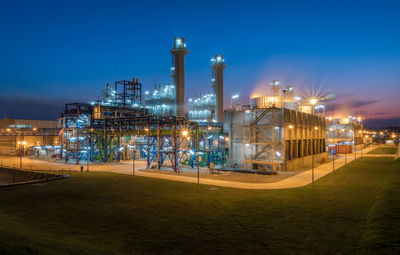 Illuminated factory against sky at night