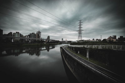 Bridge over river by buildings against sky in city