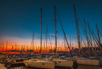 Sailboats moored on harbor against sky