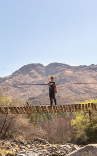 Rear view of man standing on mountain against clear sky