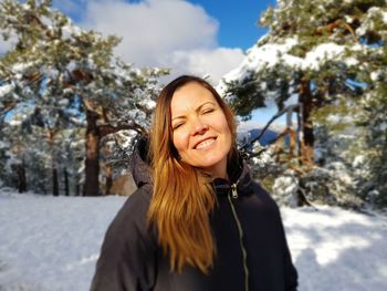 Portrait of smiling young woman standing in snow