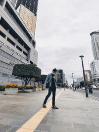 Full length of man standing on road against buildings in city