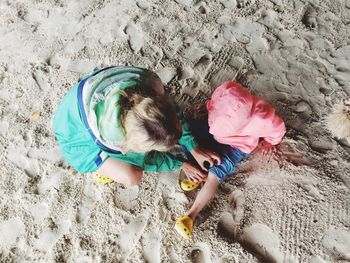 Mother adjusting daughter shoe at beach