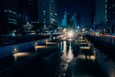 Illuminated buildings by street in city at night