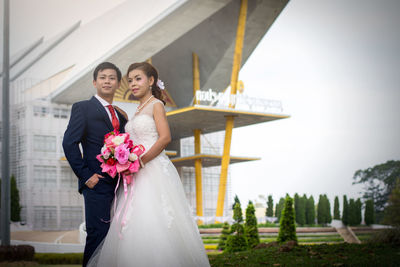 Bride and groom standing against building