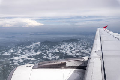 Aerial view of aircraft wing over sea against sky
