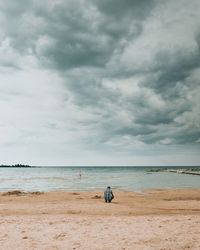 Rear view of men on beach against sky