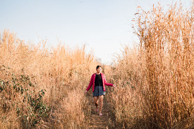 Woman walking on field against sky