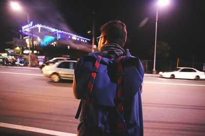 Rear view of man cycling on road at night