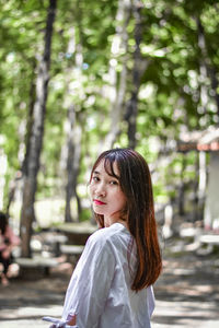 Portrait of woman standing against trees