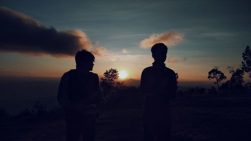 Rear view of silhouette man standing against sky during sunset