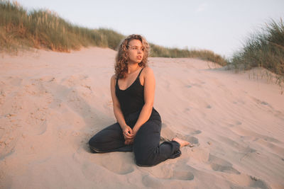 Portrait of young woman sitting on sand at beach