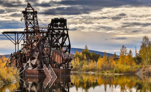 Remains of historic gold dredge no 3 in fall with reflections on the lake, steese highway, alaska