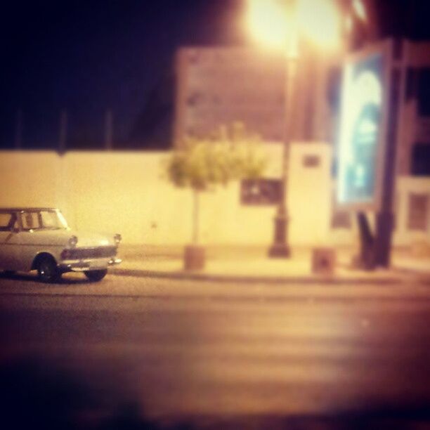 selective focus, transportation, mode of transport, land vehicle, indoors, car, illuminated, focus on foreground, night, surface level, defocused, no people, street, close-up, focus on background, communication, road, text, blurred motion, stationary