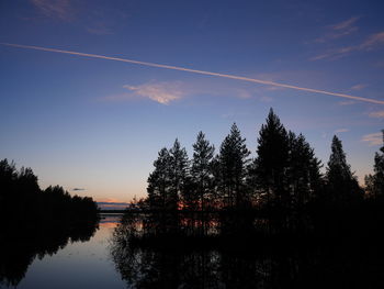 Silhouette trees by lake against sky during sunset