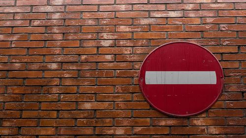 Close-up of road sign on brick wall