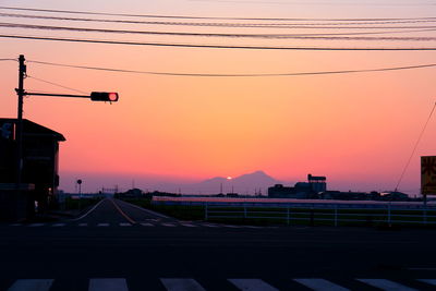 Cables over road against sky during sunset