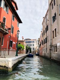 Canal amidst buildings in city against sky