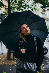 Beautiful woman with umbrella standing in rain