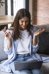 Portrait of young woman using mobile phone while sitting at home