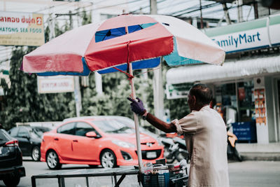 Rear view of man with umbrella on street in city