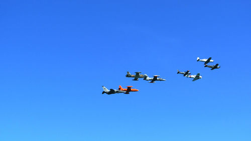 Low angle view of airplane flying against clear blue sky