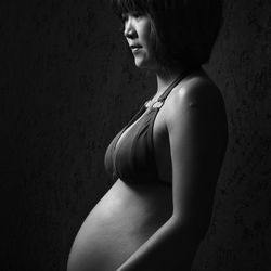 Side view of pregnant mid adult woman standing in darkroom