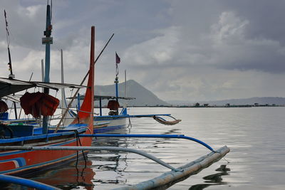 Sailboats moored on sea against sky