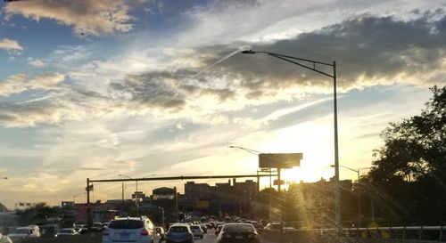 Cars on city against sky during sunset