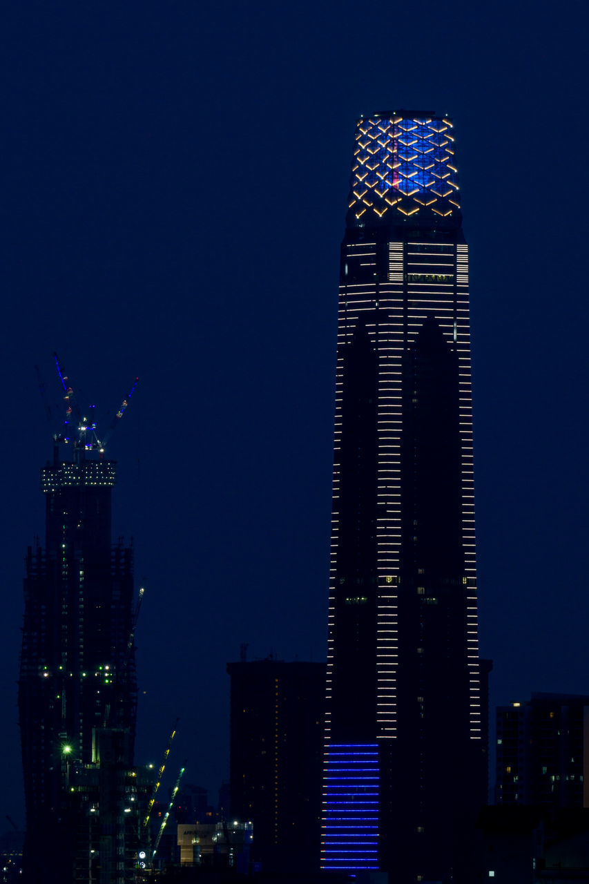 LOW ANGLE VIEW OF BUILDINGS LIT UP AT NIGHT