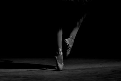 Low section of woman dancing against black background