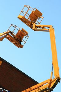 Low angle view of crane against clear blue sky