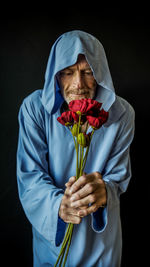 Midsection of man holding red rose against black background