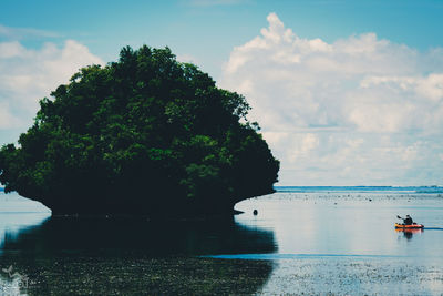 Scenic view of lake with man rowing inflatable boat against sky