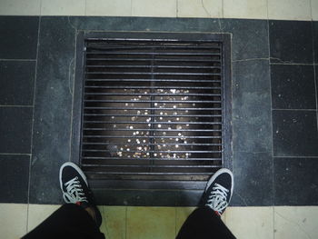 Low section of man standing on tiled floor